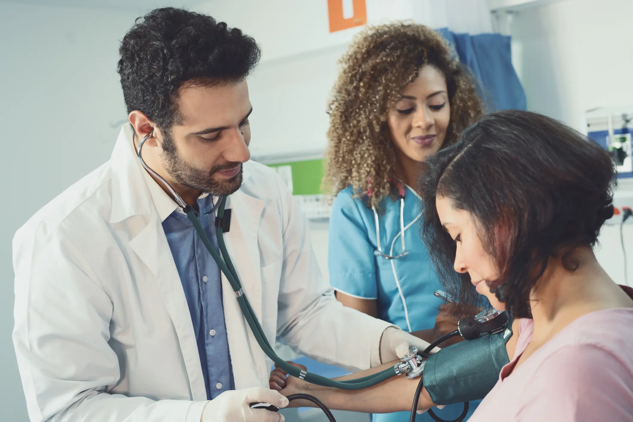 Doctor of Latin ethnicity between 25-35 years old is examining a pregnant woman in the company of a nurse