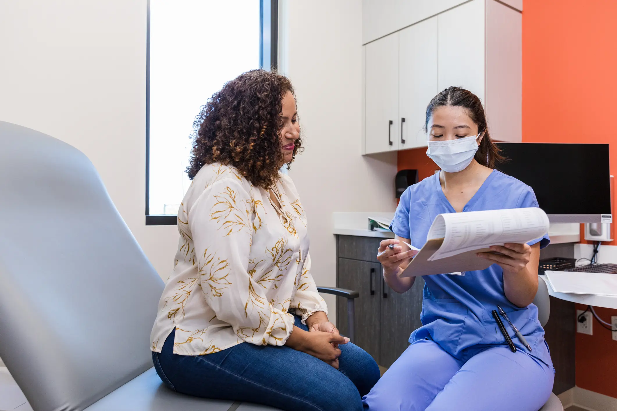 The mid adult woman smiles as the mid adult female surgeon explains the test results.
