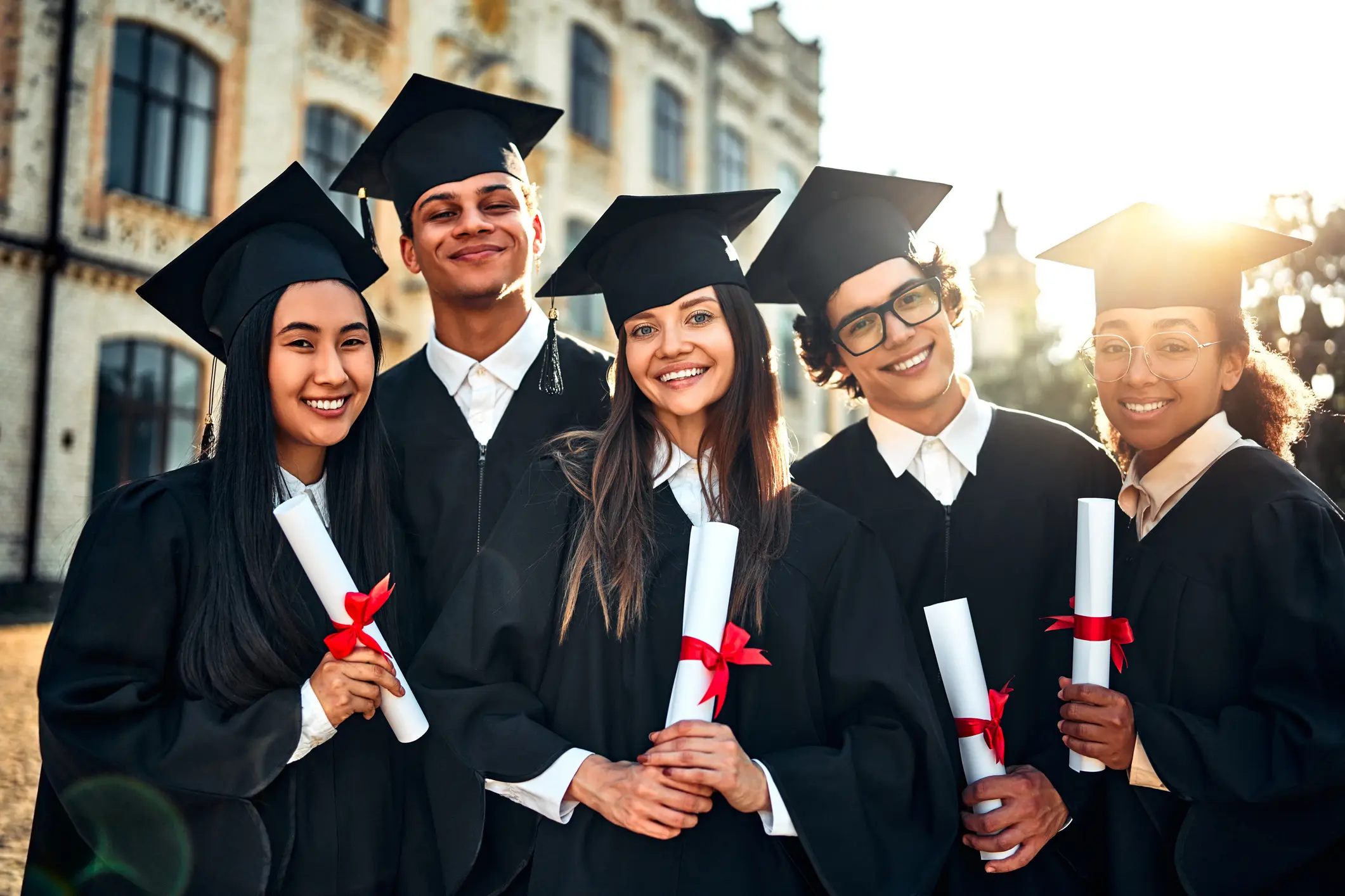 Portrait of beautiful smiling graduates celebrating graduation and holding certificates with academic goals achieved. Successful studies and a bright future.